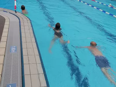 Schüler schwimmen Bahnen im Freibad