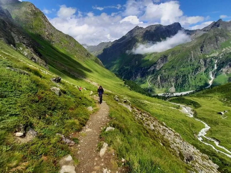 Wanderin auf einem schmalen Pfad am Berghang entlang